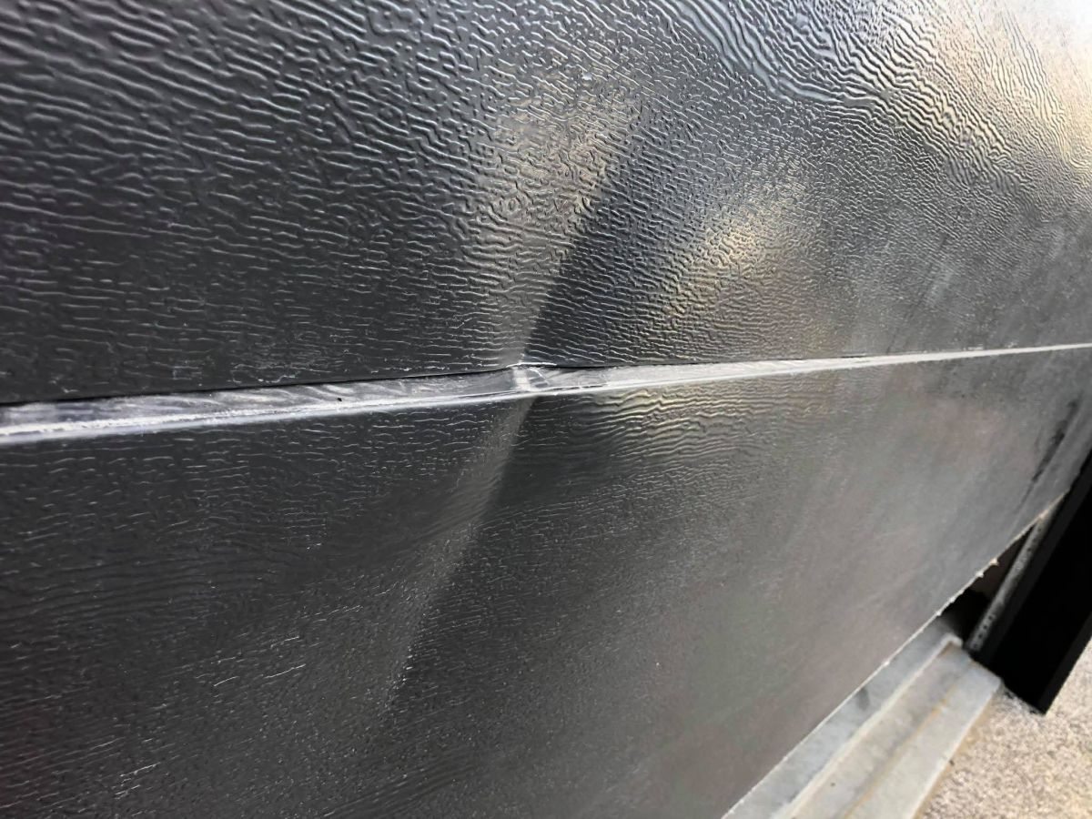 Garage roller door dent before repair Hobart